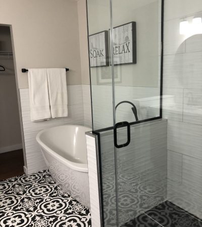 Image of a walk-in shower with seamless glass surround and a bathtub with detailed patterned floor
